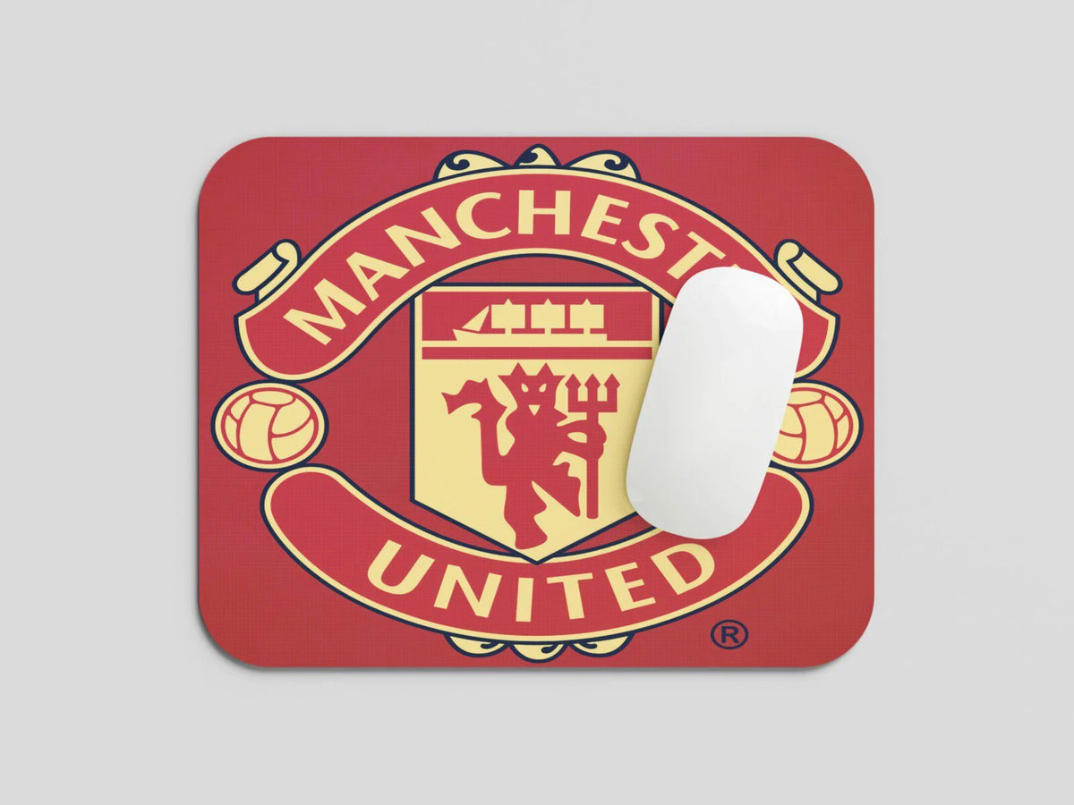 Red Manchester United small mousepad with team crest and white wireless mouse on light gray background